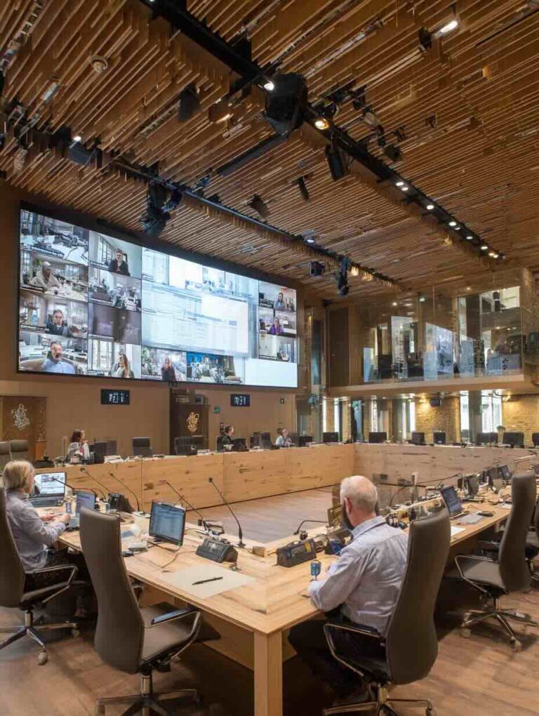 Moderne Medientechnik in einem hybriden Ratssaal mit großflächiger Videowand, Konferenzmikrofonen und Livestreaming für digitale Rats- und Ausschusssitzungen