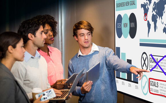 Drei Personen stehen vor einem großen interaktiven Display, auf dem Präsentationsinhalte mit der WolfVision Cynap Pro annotiert werden – ideal für kollaborative Meetings, Unterricht oder Workshops mit direkter Interaktion.