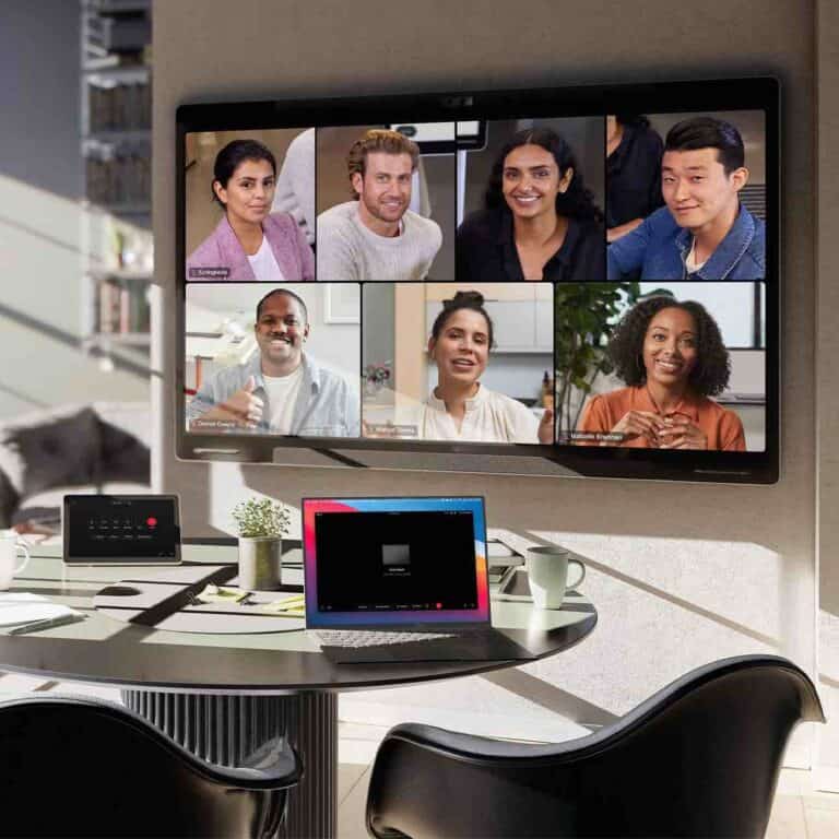 Ein Cisco Board Pro zeigt in einem kleinen Besprechungsraum eine aktive Videokonferenz mit mehreren Teilnehmern, während auf dem Tisch ein Cisco Touch Controller zur Steuerung der Sitzung genutzt wird.