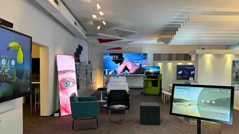 Showroom von Conference TV mit verschiedenen Medientechniklösungen, darunter interaktive Displays, Videokonferenzsysteme und moderne Raumkonzepte für hybride Zusammenarbeit.