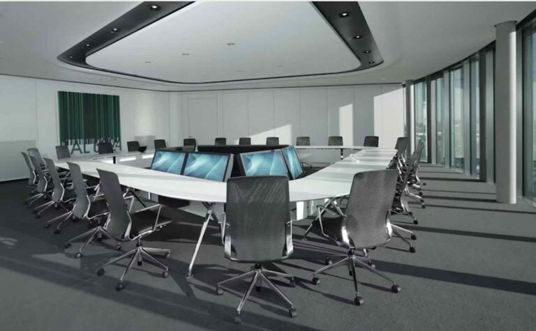 Ein moderner Boardroom mit ovalem Konferenztisch, integrierten Fröscher-Monitorinseln und hochwertigen Drehstühlen – ausgelegt für hybride Strategiemeetings, Vorstandssitzungen oder internationale Videokonferenzen.