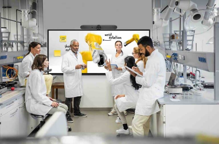 Mehrere Wissenschaftler in Laborkleidung analysieren Daten an einem interaktiven i3TOUCH ULTRA Display – geeignet für Forschung, Lehre und datengetriebene Teamarbeit im Laborumfeld.