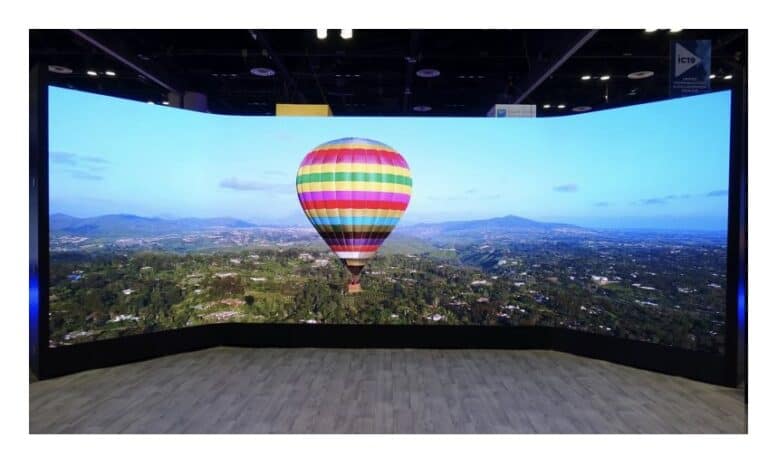 Eine stark konvex gebogene LED-Videowand aus Leyard CLI Flex Modulen zeigt eine luftige Panoramaaufnahme mit Heißluftballon über einer Stadtlandschaft, demonstriert die extreme Biegbarkeit und Bildqualität der Displaylösung in einer Indoor-Installation.
