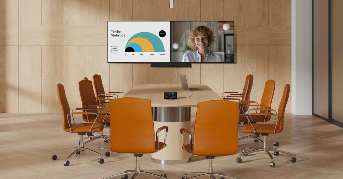 Ein moderner Konferenzraum mit mehreren Stühlen und großem Bildschirm, auf dem eine Präsentation sowie ein Videocall angezeigt werden, ausgestattet mit der Yealink MeetingBar A40 – eine All-in-One-Lösung für hybride Meetings und professionelle Videokonferenzen.