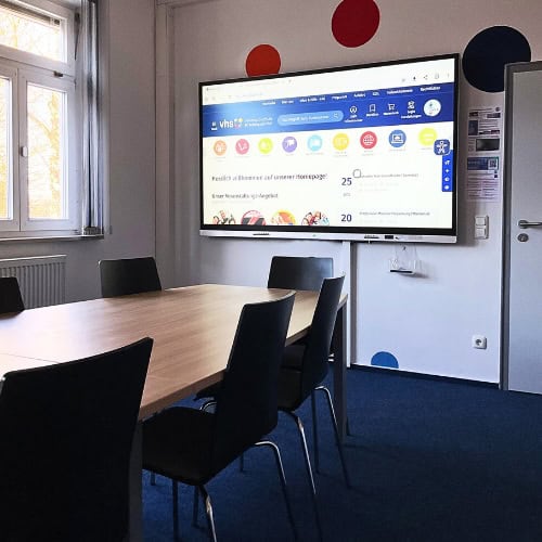 Ein interaktives PrimeBoard-Display ist in einem kleinen, hellen Unterrichtsraum der VHS Straubing installiert und unterstützt digitale Lernformate in Gruppen- und Einzeltrainings.