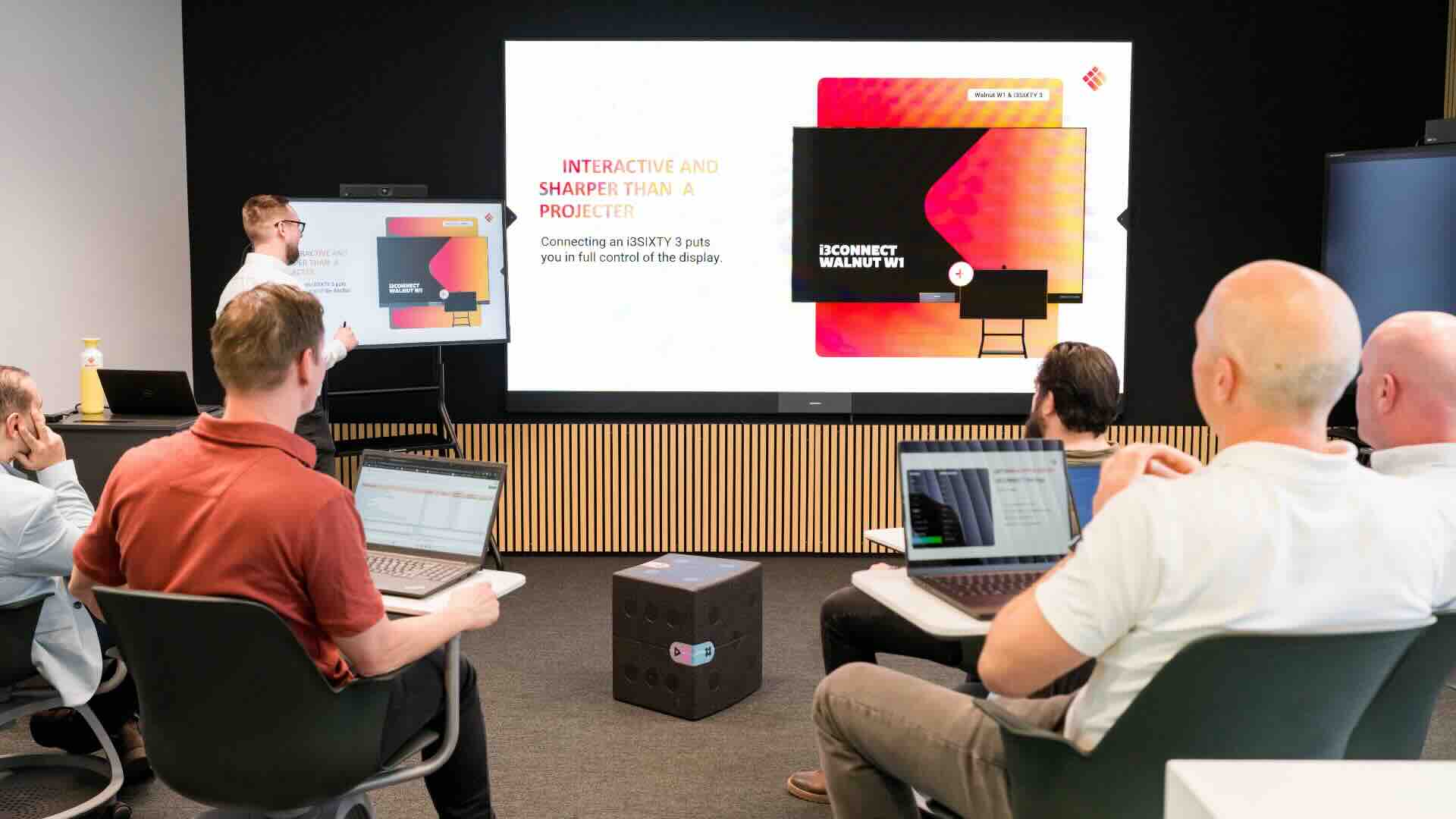 i3CONNECT Walnut W1 LED-Wand im Besprechungsraum Mehrere Personen sitzen vor einer großen LED-Wand, während eine Person die Inhalte auf der Bildschirmfläche präsentiert.