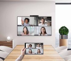 Ein moderner Besprechungsraum mit installiertem DTEN GO Videokonferenzsystem zeigt eine aktive Videokonferenz auf einem großen Display, bei der mehrere Teilnehmer remote zugeschaltet sind – ideal für hybride Meetings und Teamarbeit.