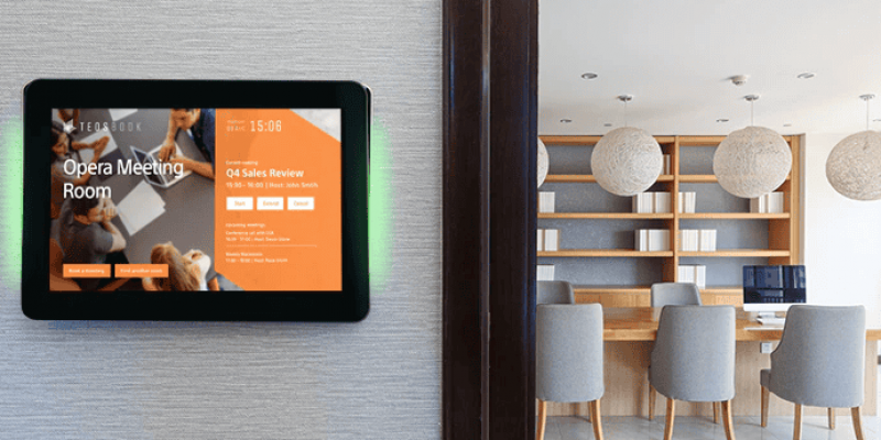 Ein Raumbuchungsterminal mit TEOS Software zeigt die aktuelle Belegung und Verfügbarkeit eines Meetingraums an – installiert an der Wand eines modernen Bürogebäudes, ideal für hybride Arbeitsplatzmodelle und effiziente Raumverwaltung.